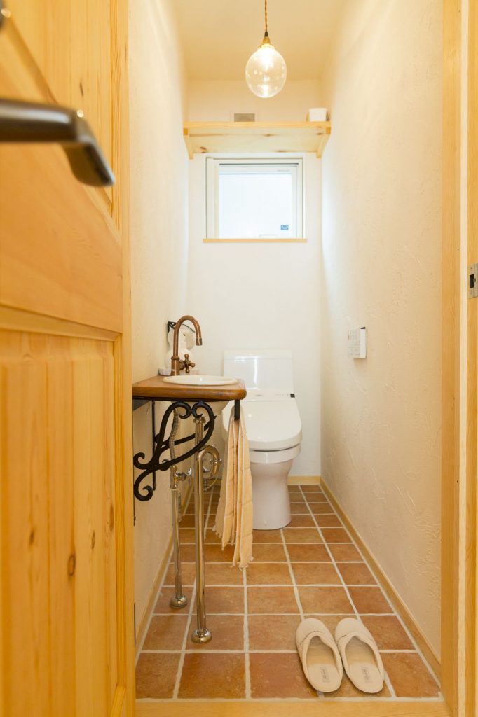 木×塗り壁×テラコッタにアンティーク調の手洗器を合わせたおしゃれなトイレ