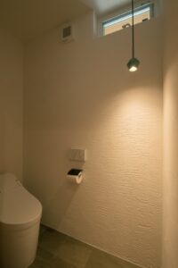 雰囲気のある照明と漆喰壁のトイレ