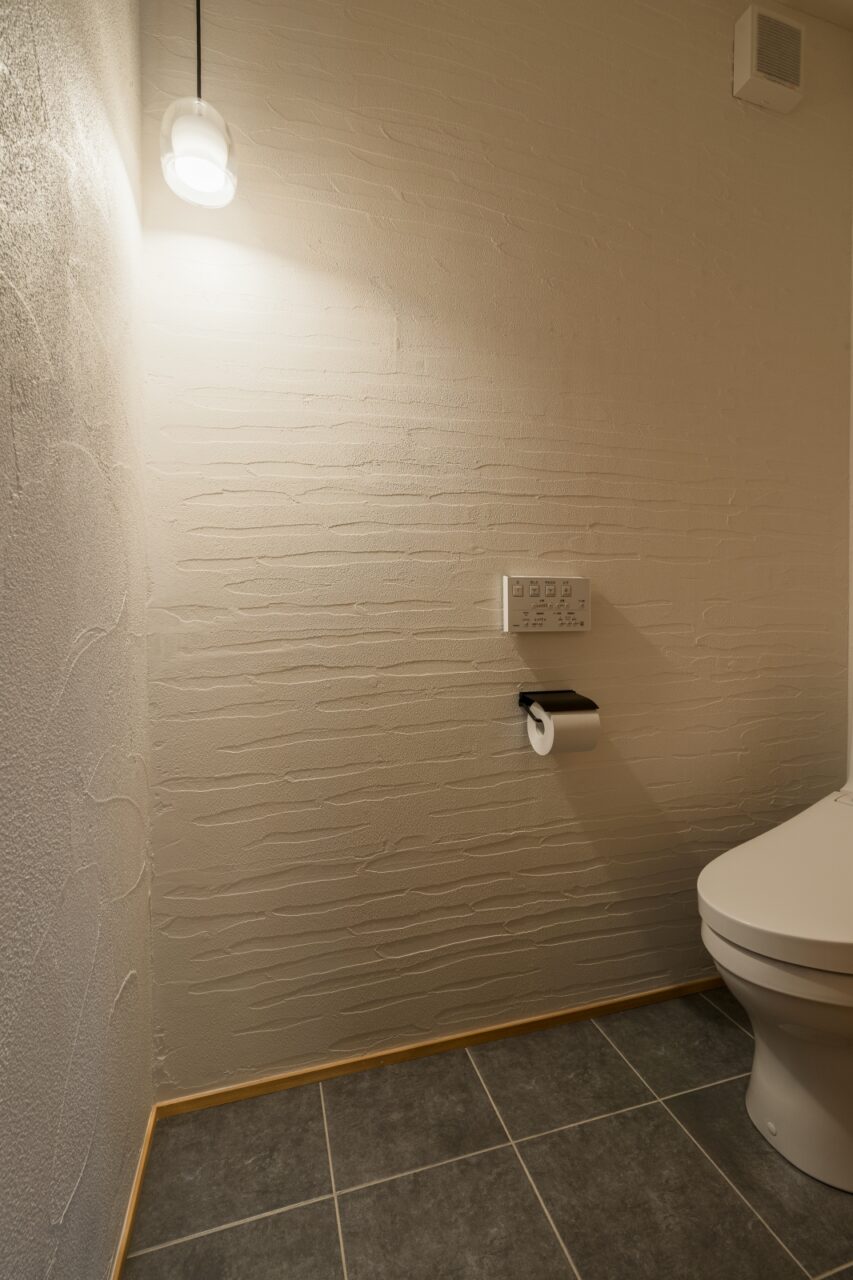 床タイルと漆喰壁のトイレ