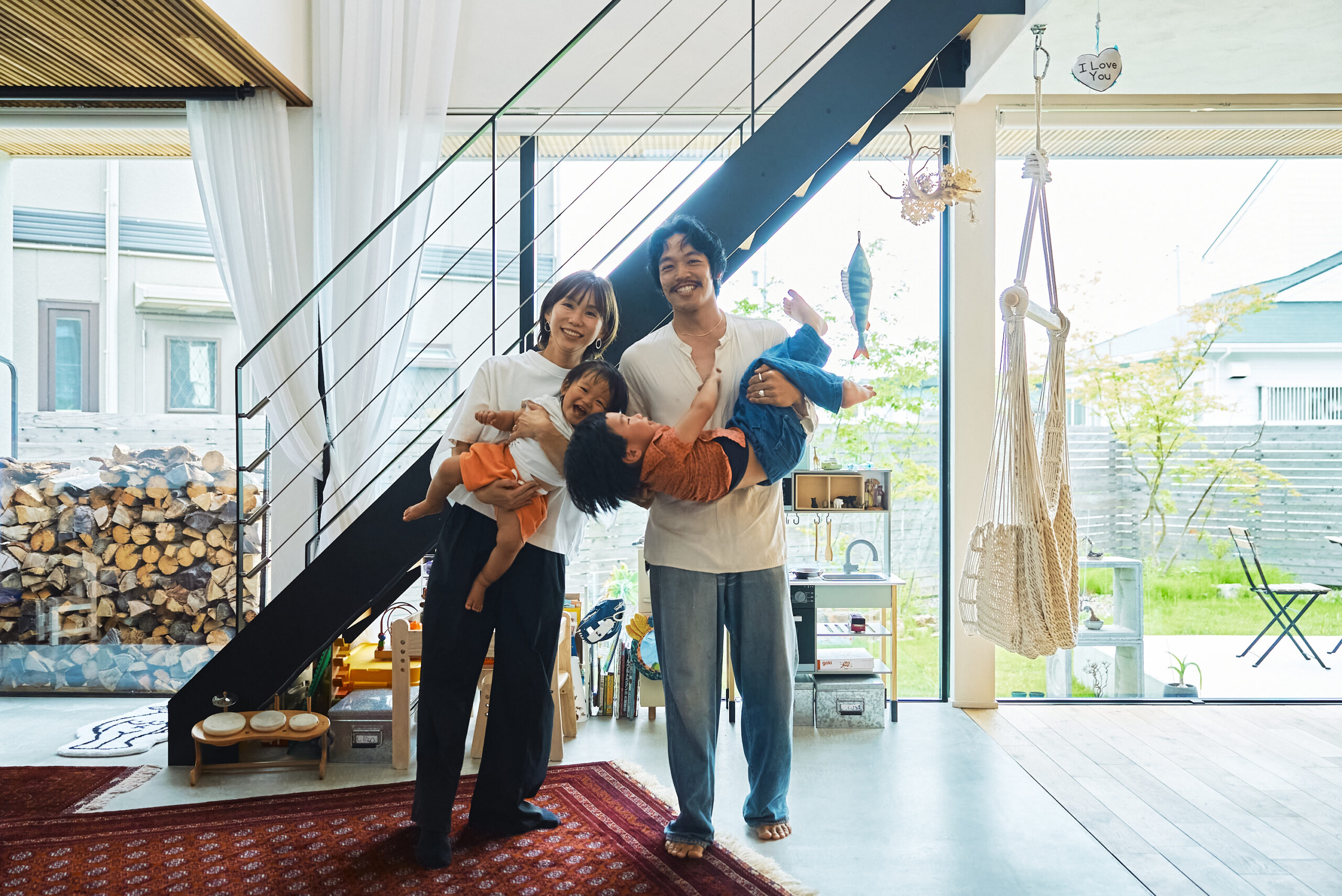 ご自宅のリビングで子どもふたりをだっこして微笑むご夫婦